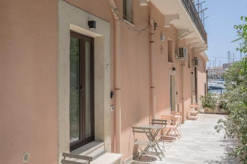 a row of chairs and tables on the side of a building at Eos - Elegants Apartments & Suites in Siracusa