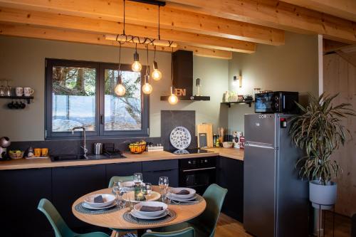 a kitchen with a table with chairs and a refrigerator at Les Gites du O' Forêt-Gîte O'rizon avec bain nordique et magnifique vue sur la plaine du forez in Verrières-en-Forez