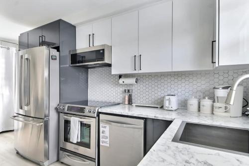 a kitchen with white cabinets and stainless steel appliances at Quebec city Downtown River Sidewalk 2 Free Parking in Quebec City