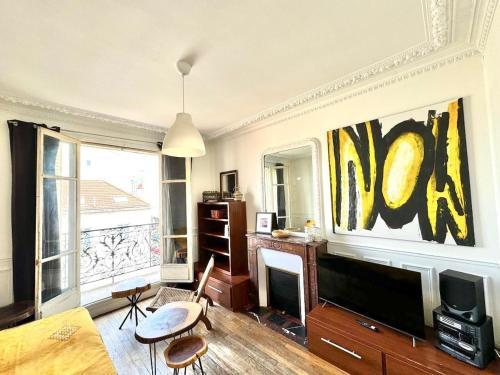 un salon avec une cheminée et un tableau au mur dans l'établissement Grand F2 Roland Garros Paris Auteuil, à Boulogne-Billancourt