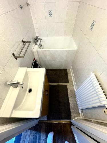 une petite salle de bain avec un lavabo blanc et une baignoire dans l'établissement Grand F2 Roland Garros Paris Auteuil, à Boulogne-Billancourt