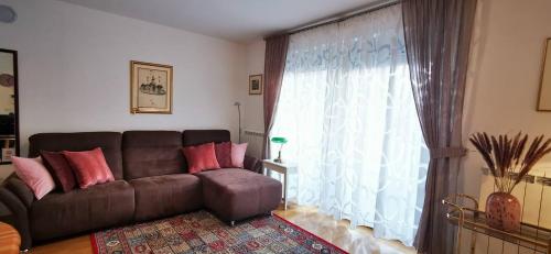 een woonkamer met een bruine bank en een groot raam bij Brand New Place in Rovinj