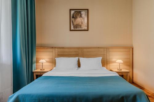 a bedroom with a bed with a blue blanket and two lamps at Seasons SPA Boutique Hotel in Kozin