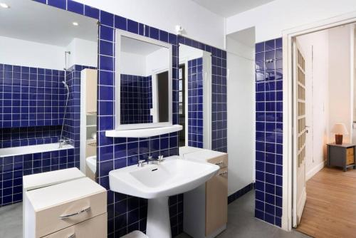 La salle de bains est pourvue de carrelage bleu, d'un lavabo et d'un miroir. dans l'établissement L'Hôtel Particulier, 120m2, Hypercentre, Wifi / ConciergerieDameCarcas, à Carcassonne