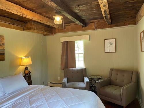 a bedroom with a bed and two chairs at The Red Country Cottage in Amenia