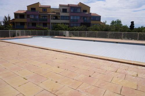 une piscine vide en face d'un bâtiment dans l'établissement Barcarelles au Barcarès Plage Piscine 5 personnes, au Barcarès