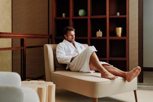 a man in a robe sitting on a chair at Signature Villa in Budva