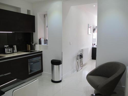 a white kitchen with a chair and a counter at BLOOMSBURY APARTMENTS in London