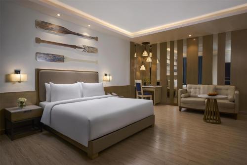 a bedroom with a large white bed and a couch at Radisson Goa Candolim in Candolim