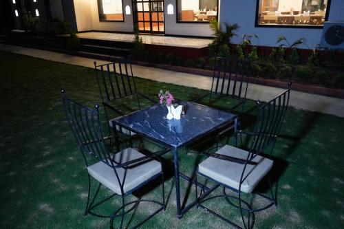 a blue table and chairs with a vase of flowers on it at Sundervan Vilas Ranthambore in Khilchipur