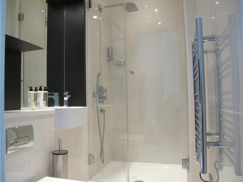 a shower with a glass door in a bathroom at BLOOMSBURY APARTMENTS in London