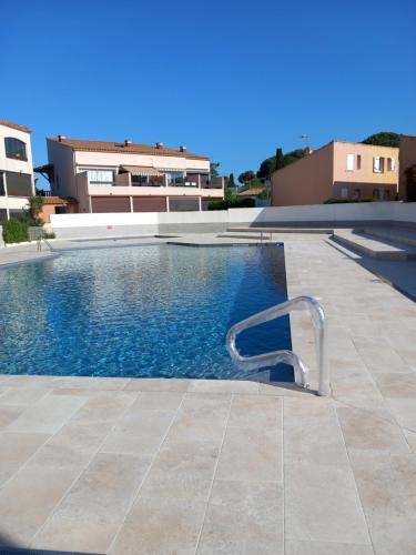 - une piscine avec une chaise à côté d'un bâtiment dans l'établissement Cap Agde studio rénové piscine, au Cap d'Agde