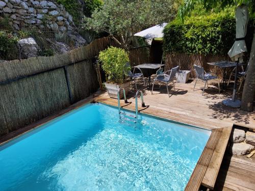 - une piscine avec une terrasse en bois, une table et des chaises dans l'établissement Le Tempo, à Entrecasteaux