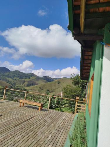 a wooden deck with a bench and mountains in the background at Pousada Verde Serena SFX in São Francisco Xavier