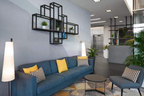 a living room with a blue couch and two chairs at Four Points Flex by Sheraton Koblenz in Koblenz