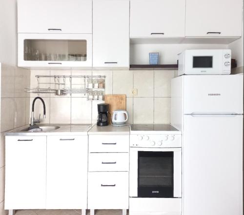 a white kitchen with white cabinets and appliances at Apartment BayView in Donji Morinj