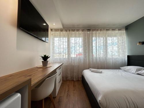 a bedroom with a bed and a desk with a television at La Suite Porcelaine, calme et chic in Panazol