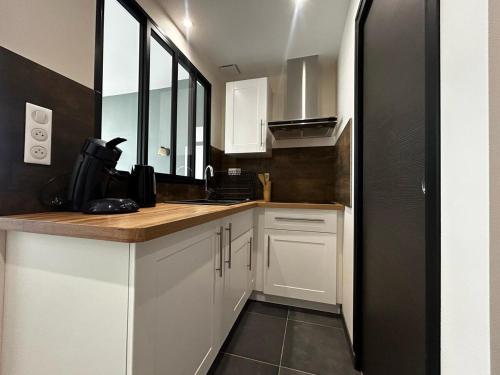 a kitchen with white cabinets and a counter top at La Suite Porcelaine, calme et chic in Panazol