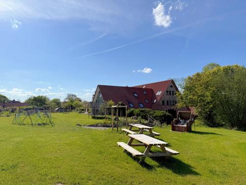 two picnic tables in a field with a playground at Timmenhus - neue Ferienwohnungen im historischen Bauernhaus in Timmendorfer Strand