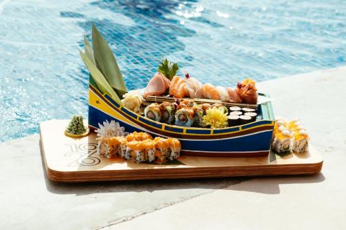 a plate of sushi on a table next to a pool at 1926 Les Bains Private Spa Suites in Sliema