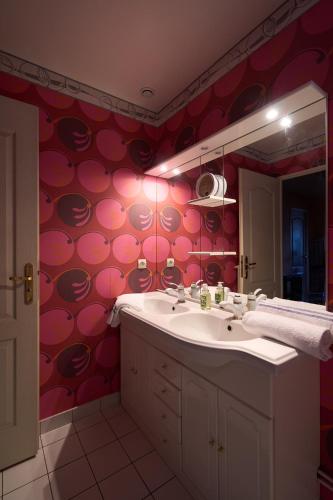 La salle de bains est pourvue d'un lavabo et d'un mur rouge. dans l'établissement Maison spacieuse avec jardin, à Boussy-Saint-Antoine