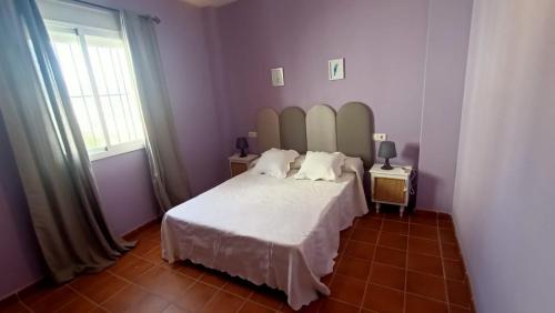 a bedroom with a white bed with a large headboard at Luz de Ardales in Ardales