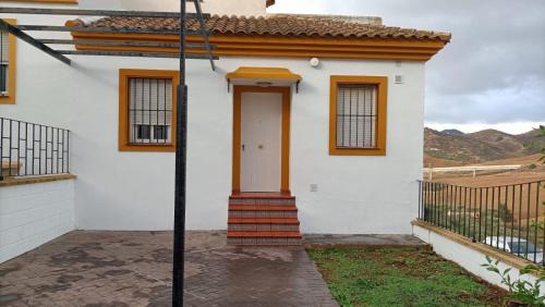 a white house with a orange door and stairs at Luz de Ardales in Ardales