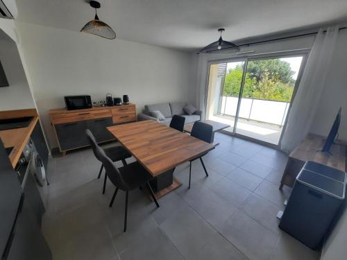 un salon avec une table et des chaises en bois dans l'établissement Appartement neuf et climatisé, 4 personnes, à 150m de la plage, à Vias