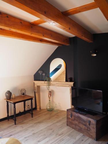 un salon avec une télévision à écran plat et une table dans l'établissement Le Dolois, à Dole