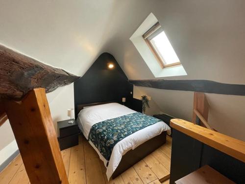 - une petite chambre mansardée avec un lit et une fenêtre dans l'établissement Le Dolois, à Dole