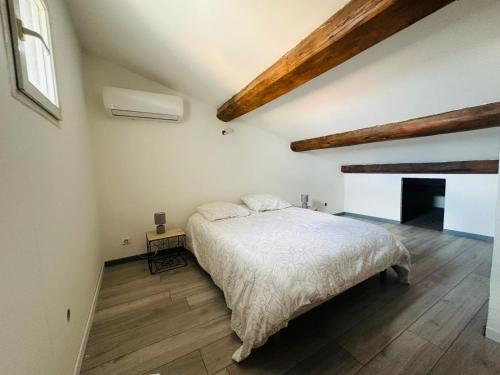 une chambre avec un lit blanc dans un grenier dans l'établissement Appartement T3 proche centre-ville NARBONNE, à Narbonne