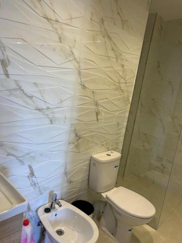 a white bathroom with a toilet and a sink at RMILATE GARDEN N6 vue sur piscine in M'diq