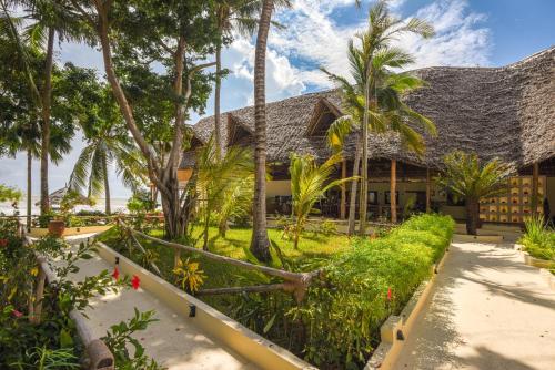 a resort with palm trees and a building at Alma Boutique Hotel in Jambiani