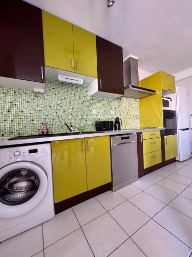 une cuisine avec des armoires jaunes et un lave-linge dans l'établissement Provencal City Center Getaway, à Saint-Raphaël