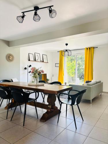 une salle à manger avec une table, des chaises et un canapé dans l'établissement Maison cosy entre Paris Rouen et Deauville, à Pont-de-lʼArche