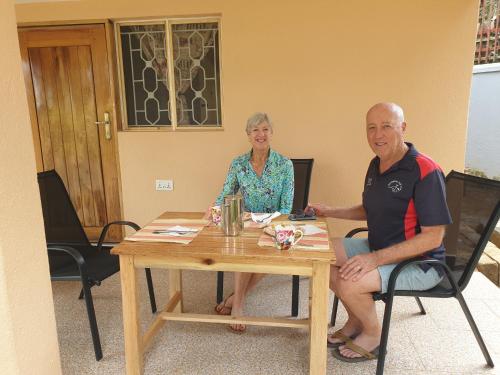 a man and a woman sitting at a table at Alison & Dave's Guesthouse in Entebbe