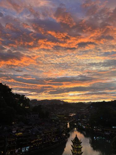 a sunset over a river with a city at Phoenix Best River View B&B in Fenghuang