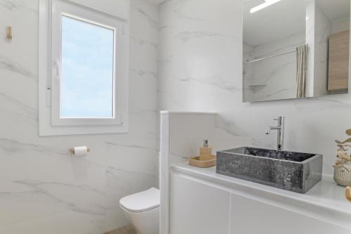 a white bathroom with a sink and a toilet at La Casita de Álvaro in Conil de la Frontera