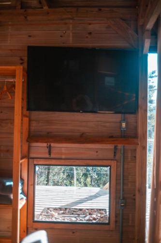 a large flat screen tv in a room with a window at Vila dos Cedros in Rio dos Cedros