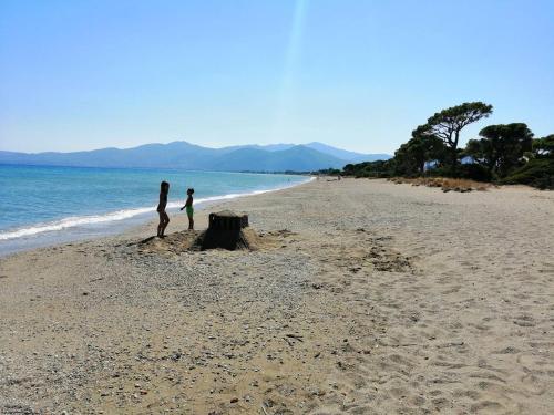 a woman and a child standing on a beach at Schinias Forest Beach House in Marathón
