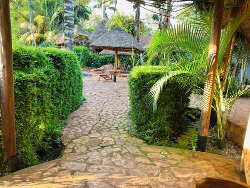 a garden with a stone walkway with a chair and umbrella at Afro Smile Hotel & Guest House in Jinja