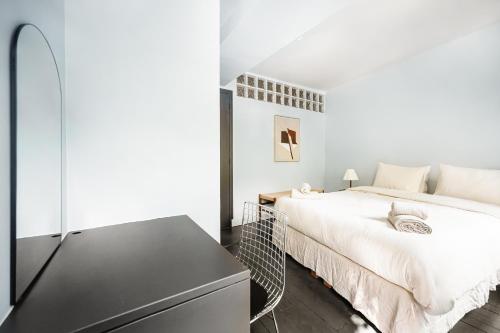 - une chambre blanche avec un lit et une commode noire dans l'établissement Elegant Parisian apartment, Place des Vosges, à Paris