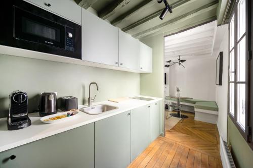 une cuisine blanche avec un évier et un micro-ondes dans l'établissement Elegant Parisian apartment, Place des Vosges, à Paris