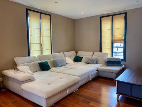 a living room with a white couch and two windows at Alery Loft in Annecy