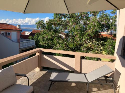 eine Terrasse mit einem Stuhl und einem Sonnenschirm auf dem Balkon in der Unterkunft Kuća za odmor-Val in Vir