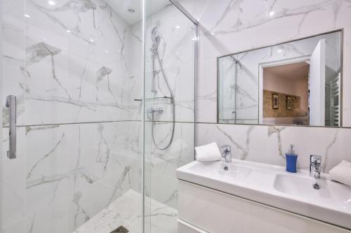 une salle de bain blanche avec un lavabo et un miroir dans l'établissement Urban Flat 74 - Disneyland in Paris Apartment, à Paris