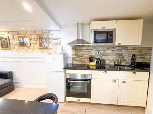 une cuisine avec des armoires blanches et un micro-ondes dans l'établissement Urban Flat 42 - Game of thrones Apartment, à Paris