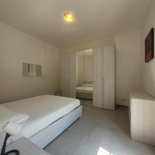 a white bedroom with a bed and a mirror at La Casetta del 26 B&B in Corsico