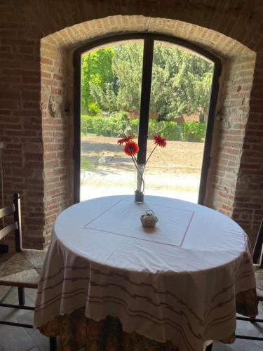 a table with a vase with red flowers on it at B&B Il Conte Giacomo in Viarolo