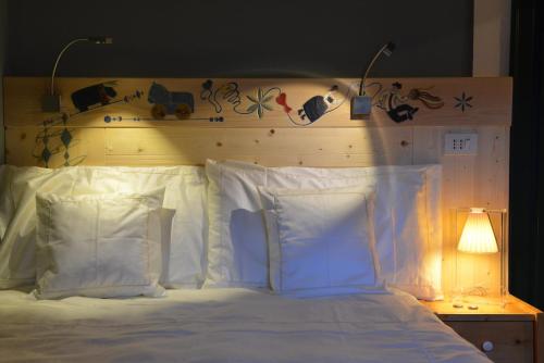 a bed with white pillows and a wooden headboard at Hotel Du Grand Paradis - 1899 Auberge Boutique in Cogne